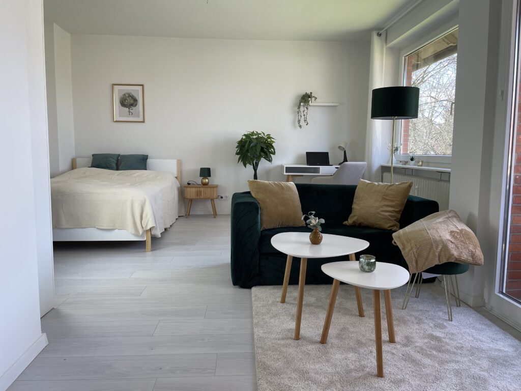 Blick vom Wohnbereich in den Schlafbereich & Schreibtisch: Sofa und Bett klar getrennt, ohne eine einzige Trennwand. Zonierte Einzimmerwohnung