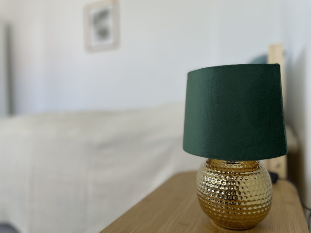 Detailaufnahme Farbwelt Nachttisch & Lampe, Zeigt: das Zusammenspiel von Grün, Gold und warmen Tönen